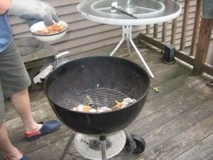 Adding soaked wood chips to the hot charcoal