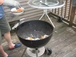 Adding soaked wood chips to the hot charcoal