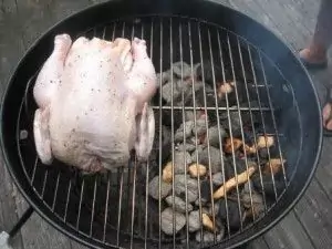 Chicken placed on grill on opposite side of charcoal